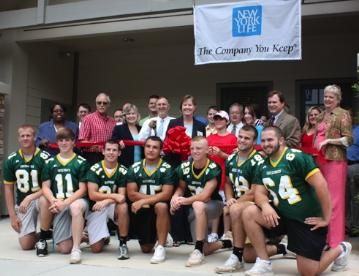 Kendra Financial team members posing with football team during grand opening